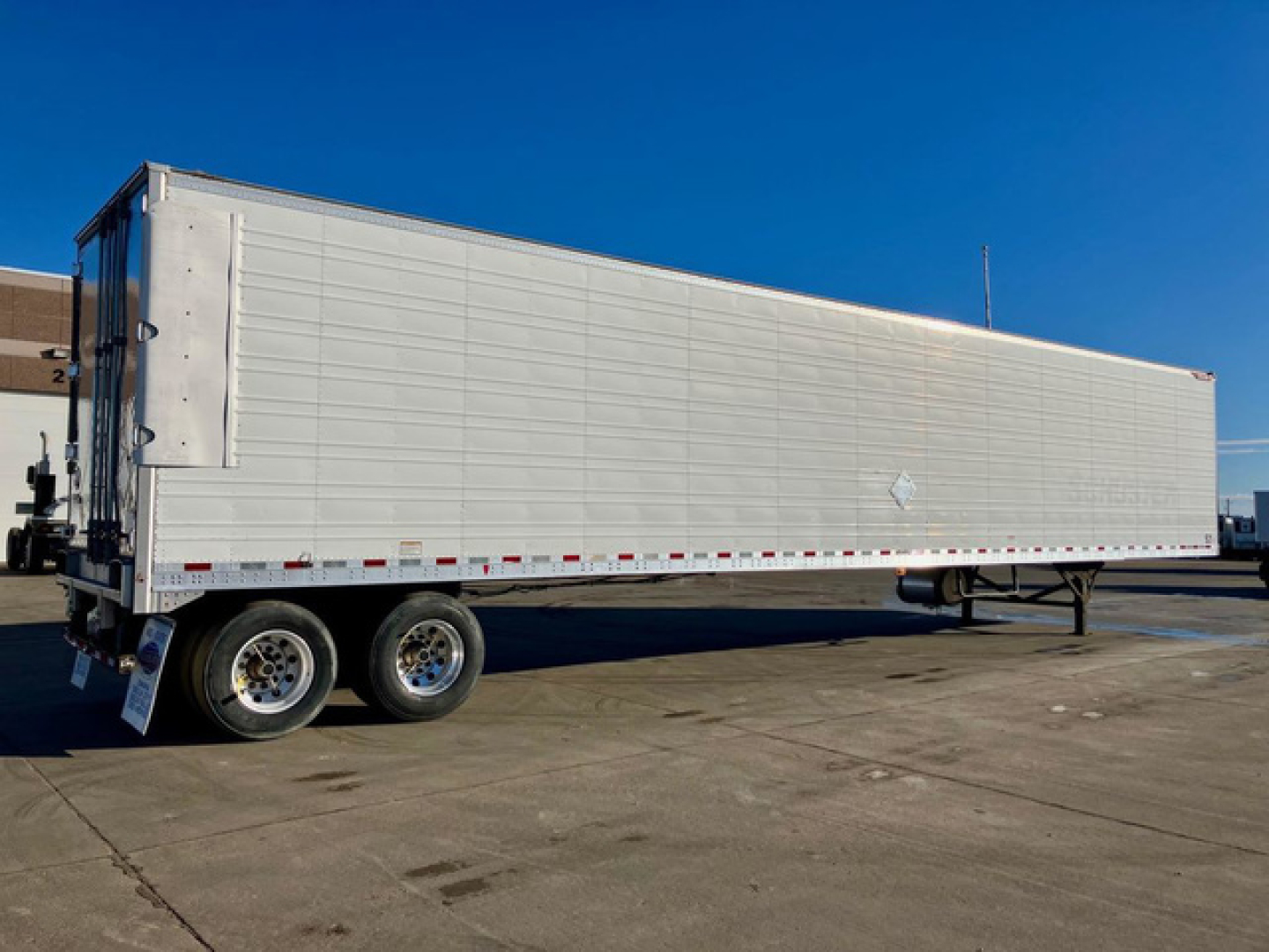 Great Dane reefer trailer side view with silver aluminum panels, dual rear axles, and a reefer unit not visible; plain blue sky.