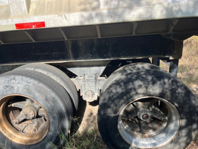 Trailer axle area showing dual wheels on a dump trailer with metal frame and undercarriage details.