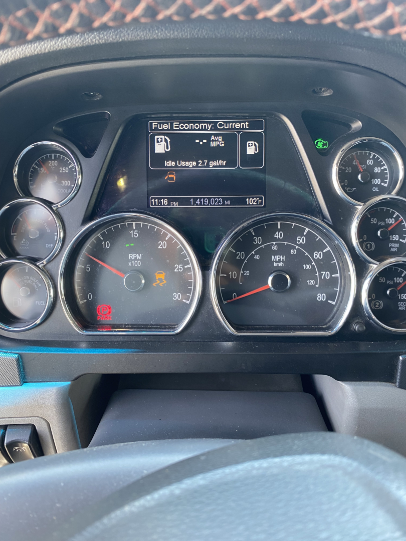 Dash view of a 2015 Peterbilt 567 instrument cluster showing fuel economy information on center display and multiple gauges.