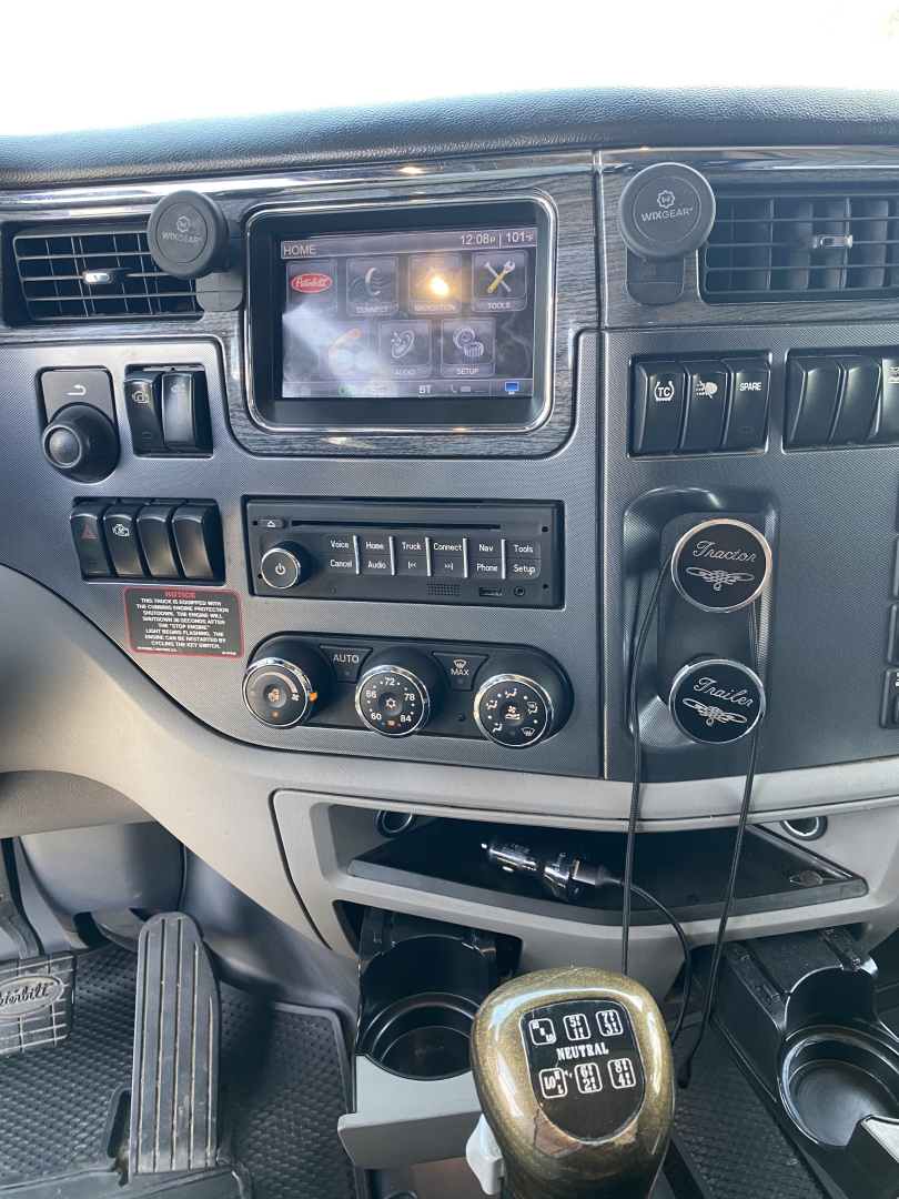 Peterbilt 567 cab interior showing dashboard touchscreen, climate controls, and gear shifter.
