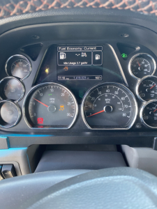 Dash view of a 2015 Peterbilt 567 instrument cluster showing fuel economy information on center display and multiple gauges.