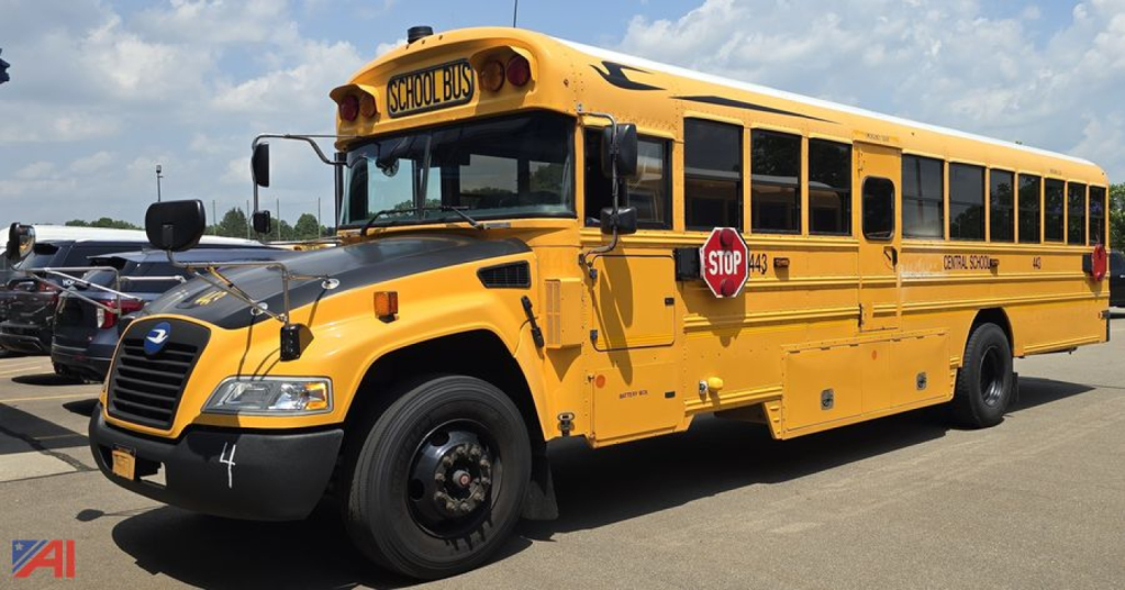 School bus side view showing blue bird logo, yellow body, stop sign extended, front grille and wheel visible.