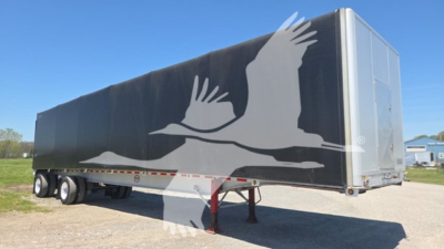 Curtainside trailer showing large white bird graphic on dark side panel with front cab in view