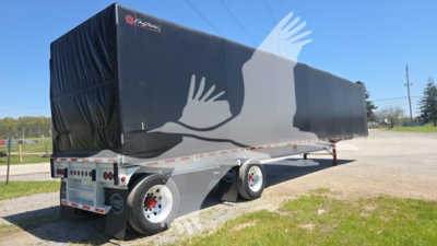 Trailer with covered curtainside of a 2013 Mac Alum Flat 72K Beam showing black tarp and dual rear axles.