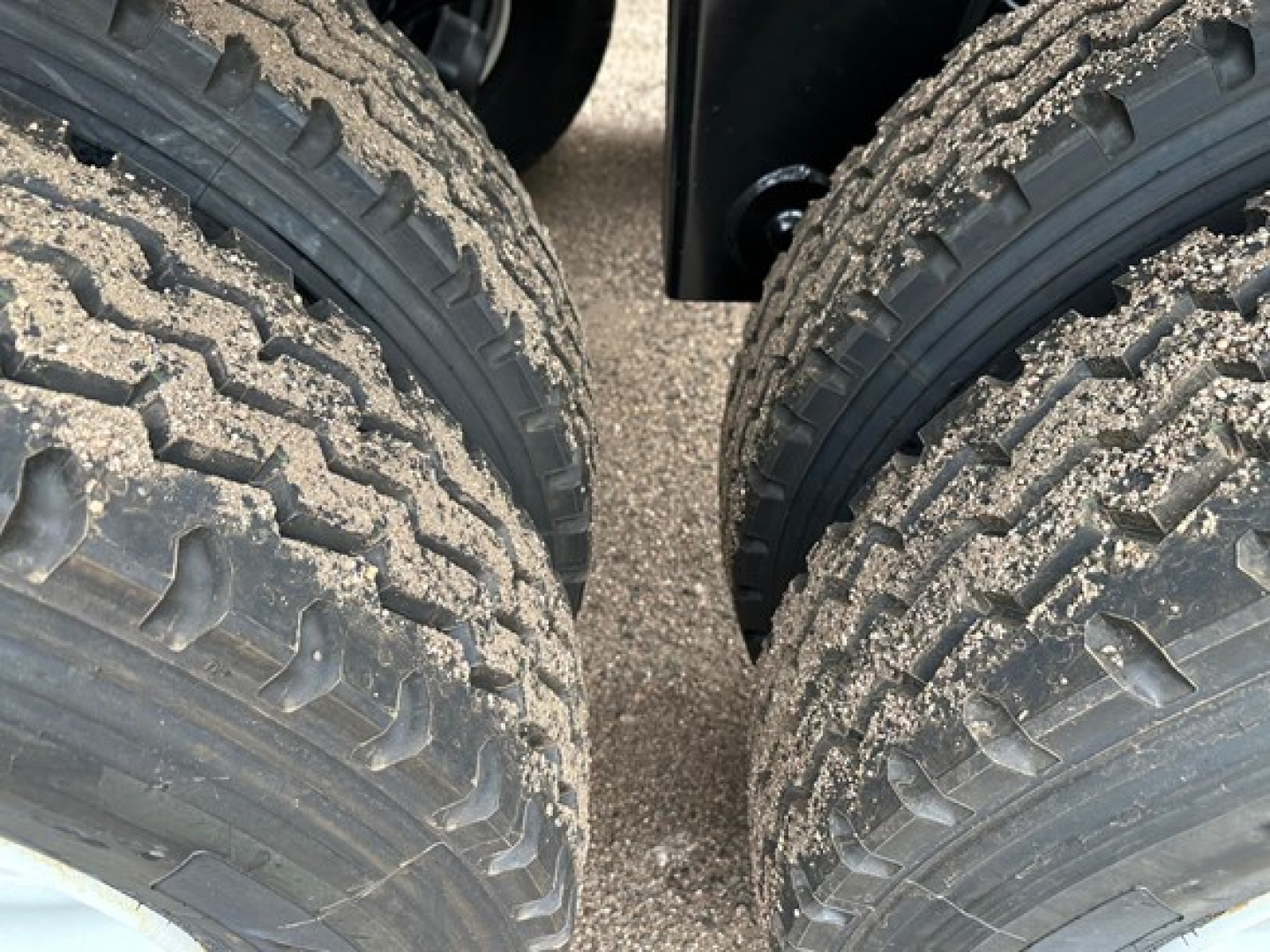 Twin rear wheels of a dump trailer showing rugged tread and mud, part of a 2026 Ranco LW21-40 trailer.