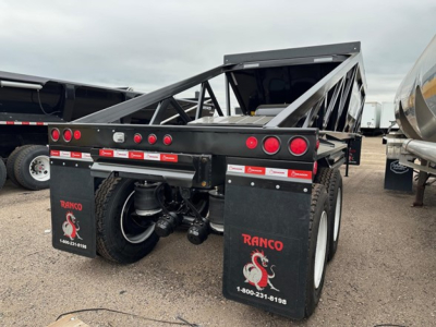 Trailer rear view showing Ranco LW21-40 industrial dump trailer with black frame, dual axles, mud flaps labeled RANCO with phone number 1-800-231-5198.