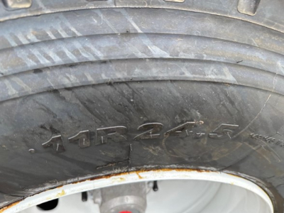 Trailer wheel and tire close-up showing rugged tire with embossed markings; partial orange-rust on wheel rim edge.
