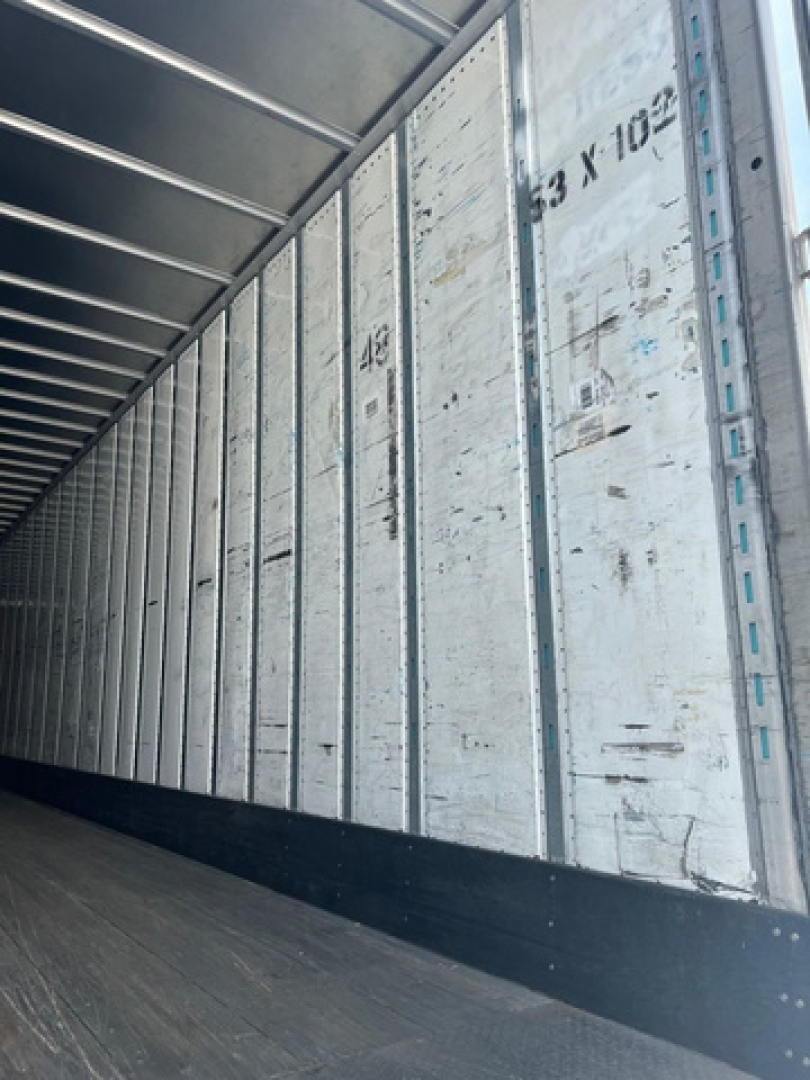 Interior of a utility van trailer showing corrugated metal walls with vertical support channels and numbered markings along the side.