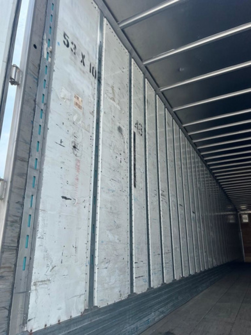 Trailer interior showing metal wall panels with vertical tracking and faint numbers, cargo area of a 2012 utility van trailer.