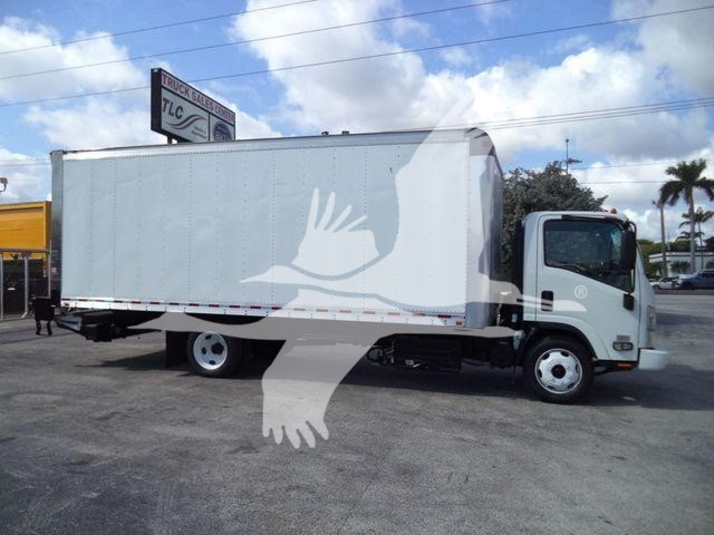 Isuzu NPR/box truck side view showing stock number 210707FM listing, box truck body, cab at front, clear sky.