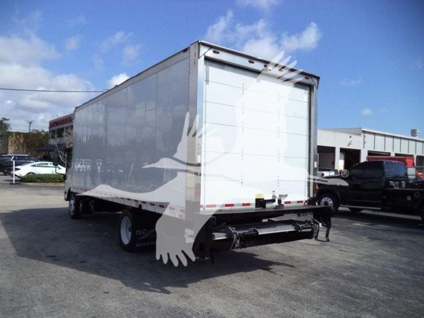 Isuzu NPR box truck in rear-side view showing cargo box and rear doors.