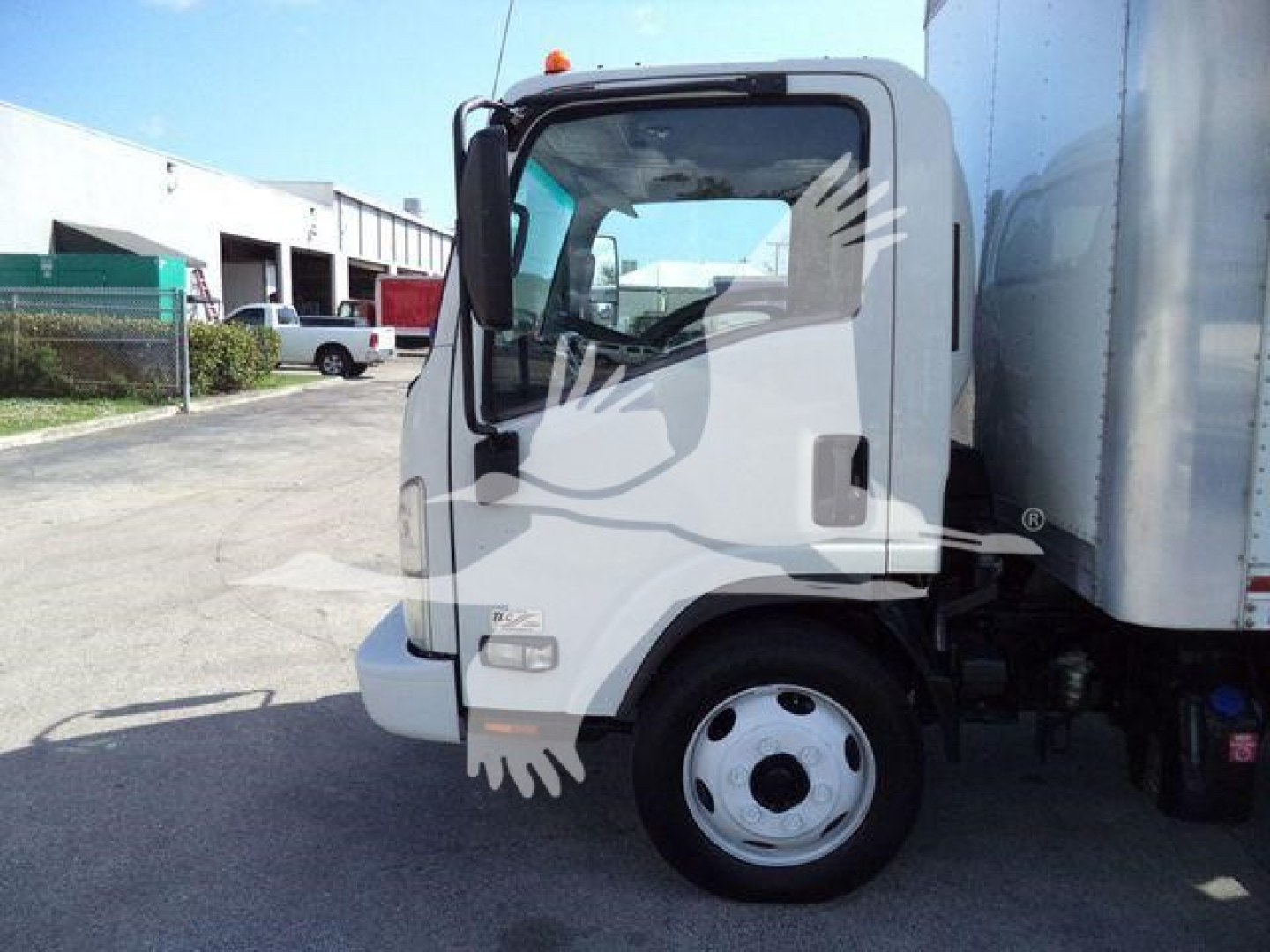 Isuzu NPR truck cab side view showing front wheel and box truck body.