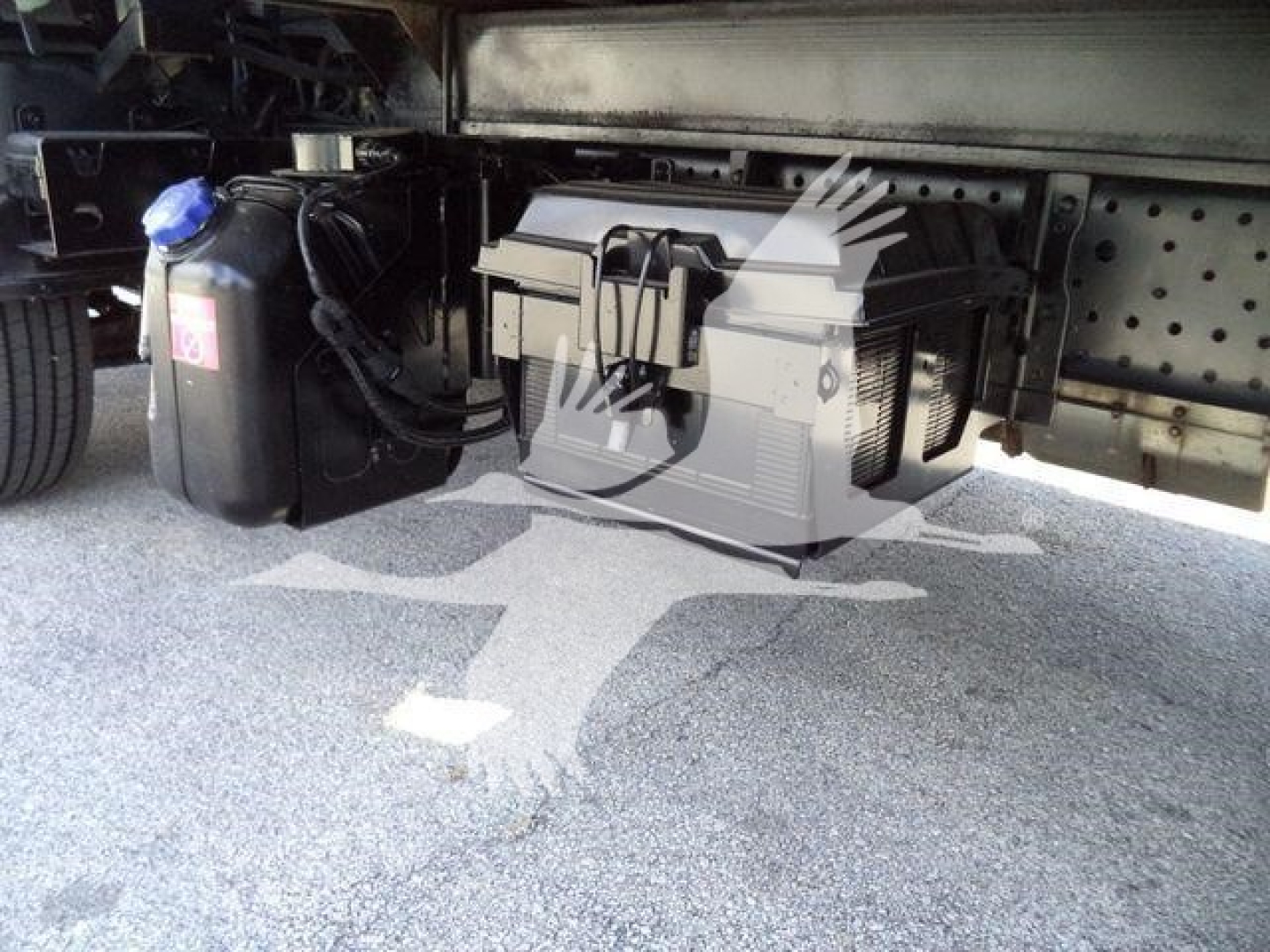 Undertray of Isuzu NRR showing toolbox and fluid reservoir with hoses and frame members visible.