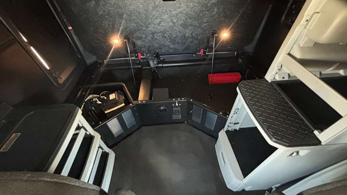 Kenworth T680 truck cab interior showing dashboard area and sleeper space with storage compartments.