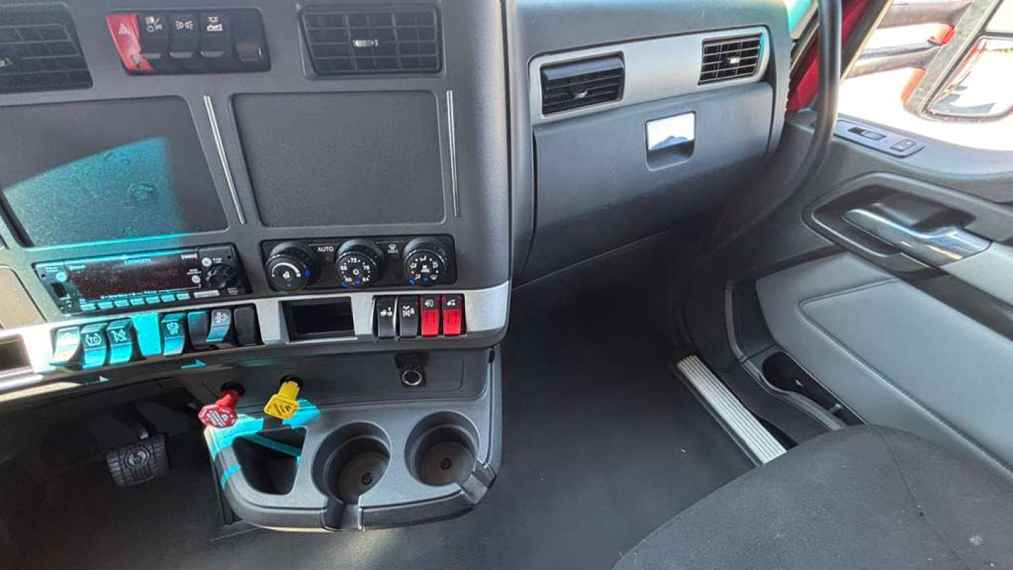 Kenworth T680 cab interior showing dashboard controls and storage compartments with blue and red tags.