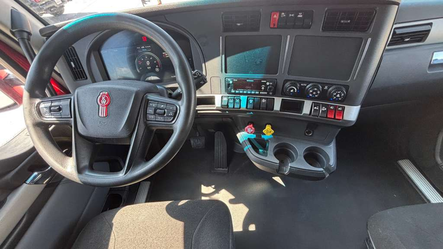 Kenworth T680 truck cockpit showing steering wheel, dashboard, and center console with gauges and controls.