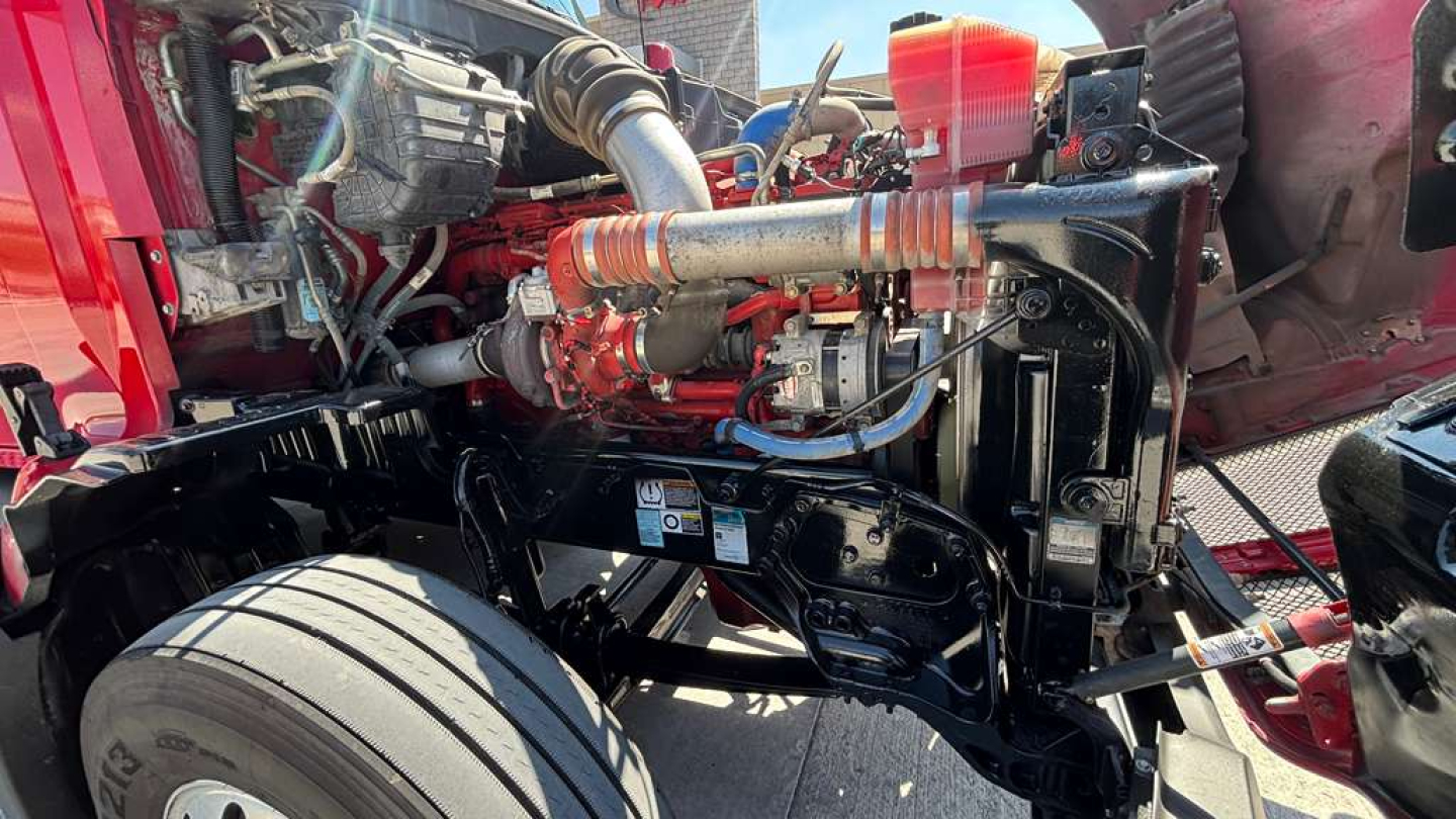 Kenworth truck engine bay showing high-performance fuel lines, turbo, and coolant reservoir with exposed chassis and wheel nearby.