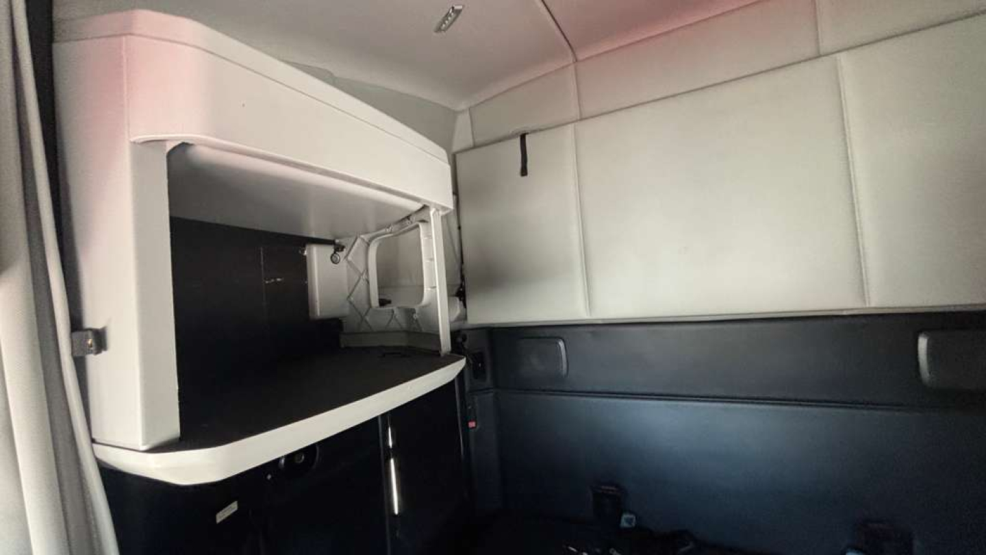 Kenworth T680 sleeper cab interior showing overhead storage cabinet and side wall panels.