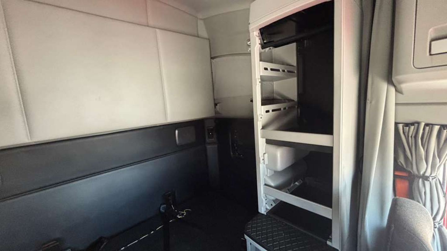 Kenworth T680 truck interior showing sleeper cab with open storage shelves and cab wall panels.