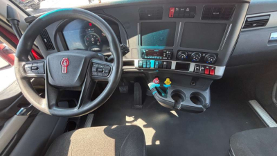 Kenworth T680 truck cockpit showing steering wheel, dashboard, and center console with gauges and controls.