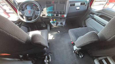 Kenworth T680 cab interior showing steering wheel, dashboard, and front seats.