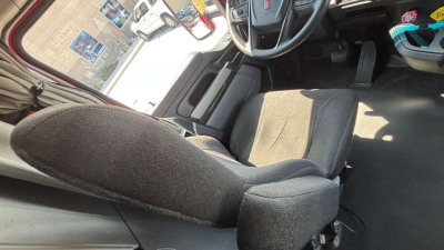 Truck interior showing driver's seat and steering wheel area, with partial view of dashboard and pedals.