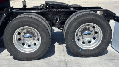 Kenworth T680 rear dual rear axles with wheel rims and tires visible, chassis frame and drive line components at top of image.