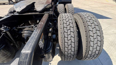 Dual rear tires and chassis of a Kenworth truck showing tire tread and suspension components.