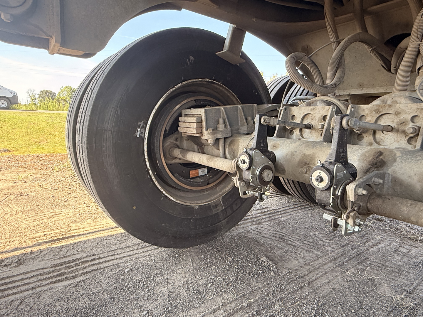 Trailer axle showing wheel and suspension components with bolts and air line fittings visible.