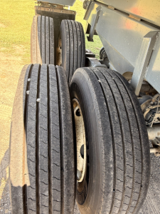 Dual rear tires and wheel assemblies of a dump trailer showing multiple tires on axles.