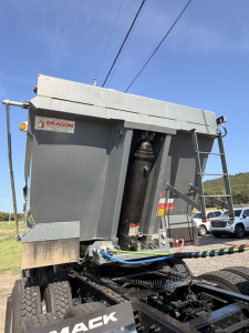 Dump trailer rear view showing hydraulic cylinder and Dragon equipment label on the end dump body.