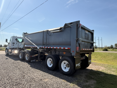 Dump trailer showing rear and side panels with Ranco END DUMP branding on the bed; tandem axle wheels and rear tailgate visible.