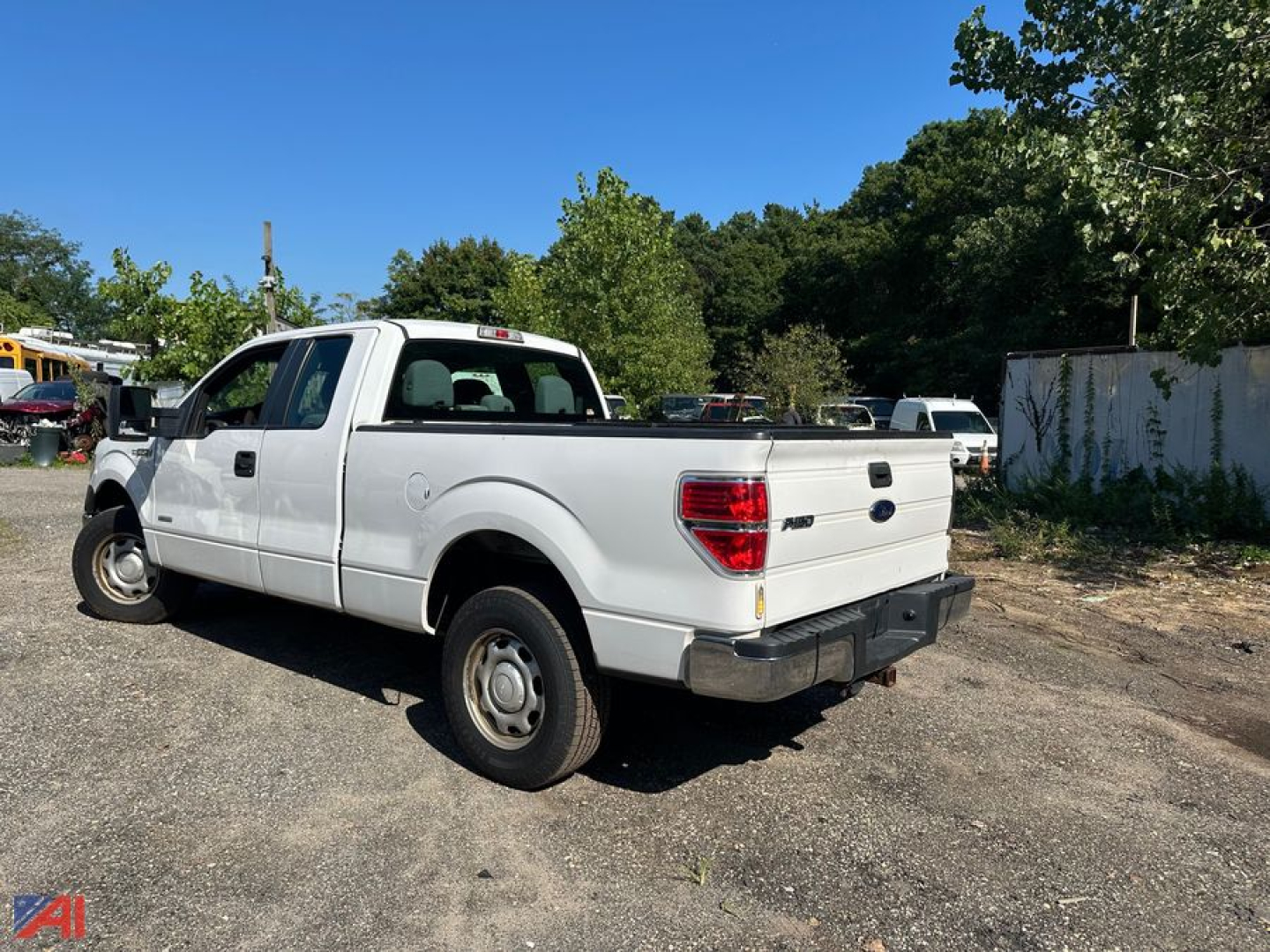 Ford F-150 pickup truck extended cab rear three-quarter view showing white body, 4x4, dual rear doors, plain bed, basic steel wheels.