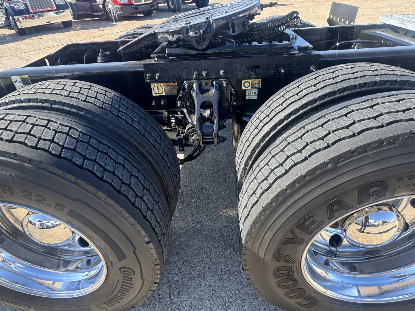 Peterbilt 579 tractor undercarriage showing dual rear axles and suspension with chrome rims and Goodyear tires; visible battery and hitch area; no plate information.