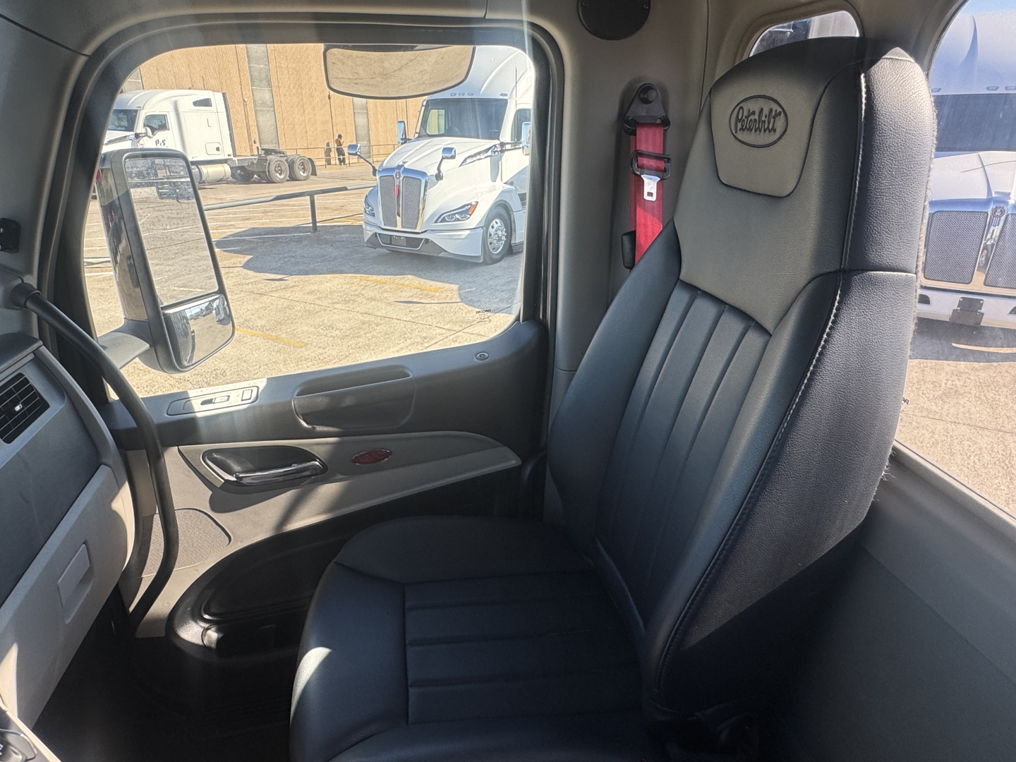 Interior of a Peterbilt 579 cab showing driver seat with Ring Gen 3 headrest, seat belt, door panel, and window view.
