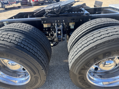 Peterbilt 579 tractor undercarriage showing dual rear axles and suspension with chrome rims and Goodyear tires; visible battery and hitch area; no plate information.
