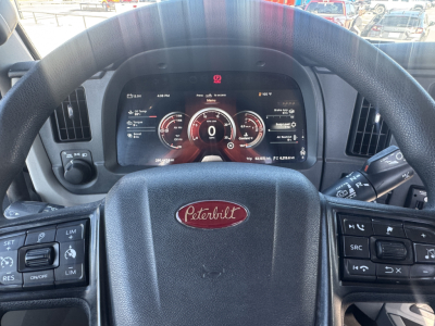 Peterbilt 579 interior dash with steering wheel and digital instrument cluster showing speedometer at 0, various gauges, and steering wheel badge.