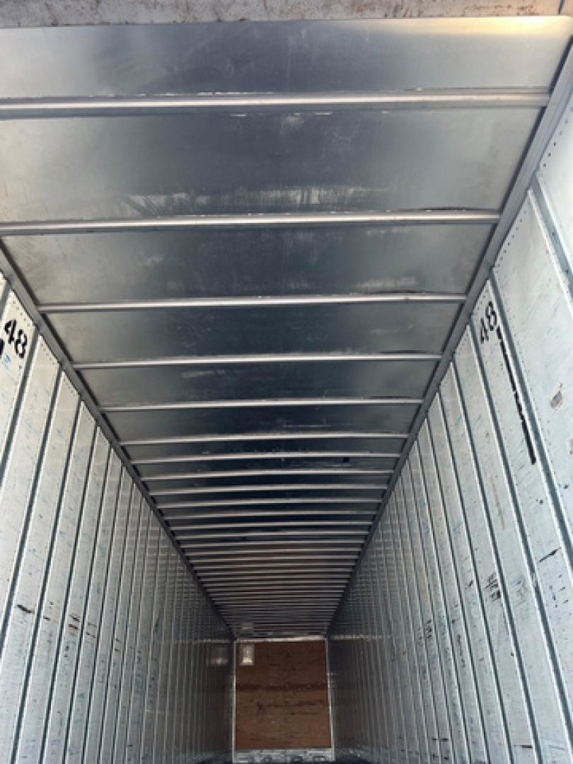 Trailer interior showing corrugated metal walls and ceiling with numbered vertical tracks; long narrow cargo space in a utility van/trailer.