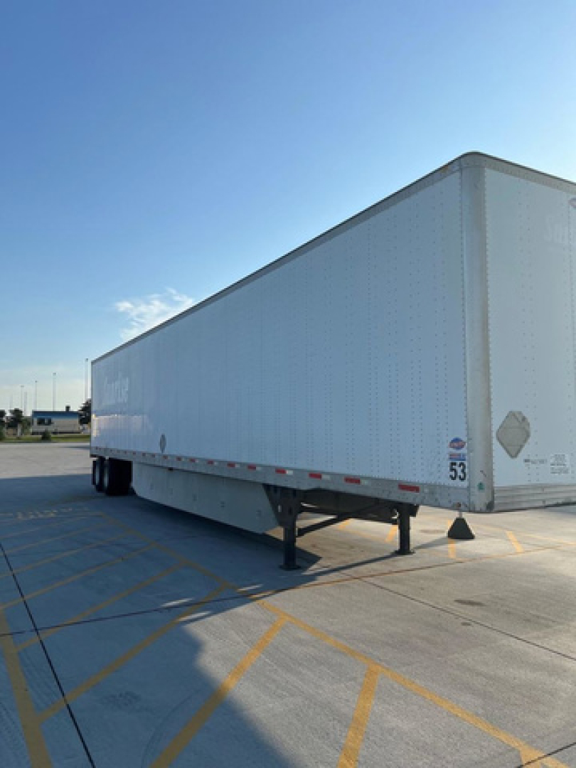 Trailer unit showing side view of a white utility van trailer with plate and support legs visible.