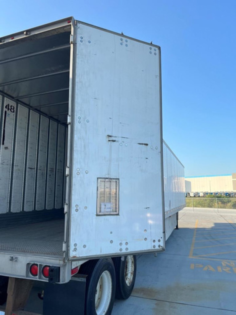 Utility van trailer rear and side showing open rear doors, light blue aluminum box with interior cargo area and flooring visible.