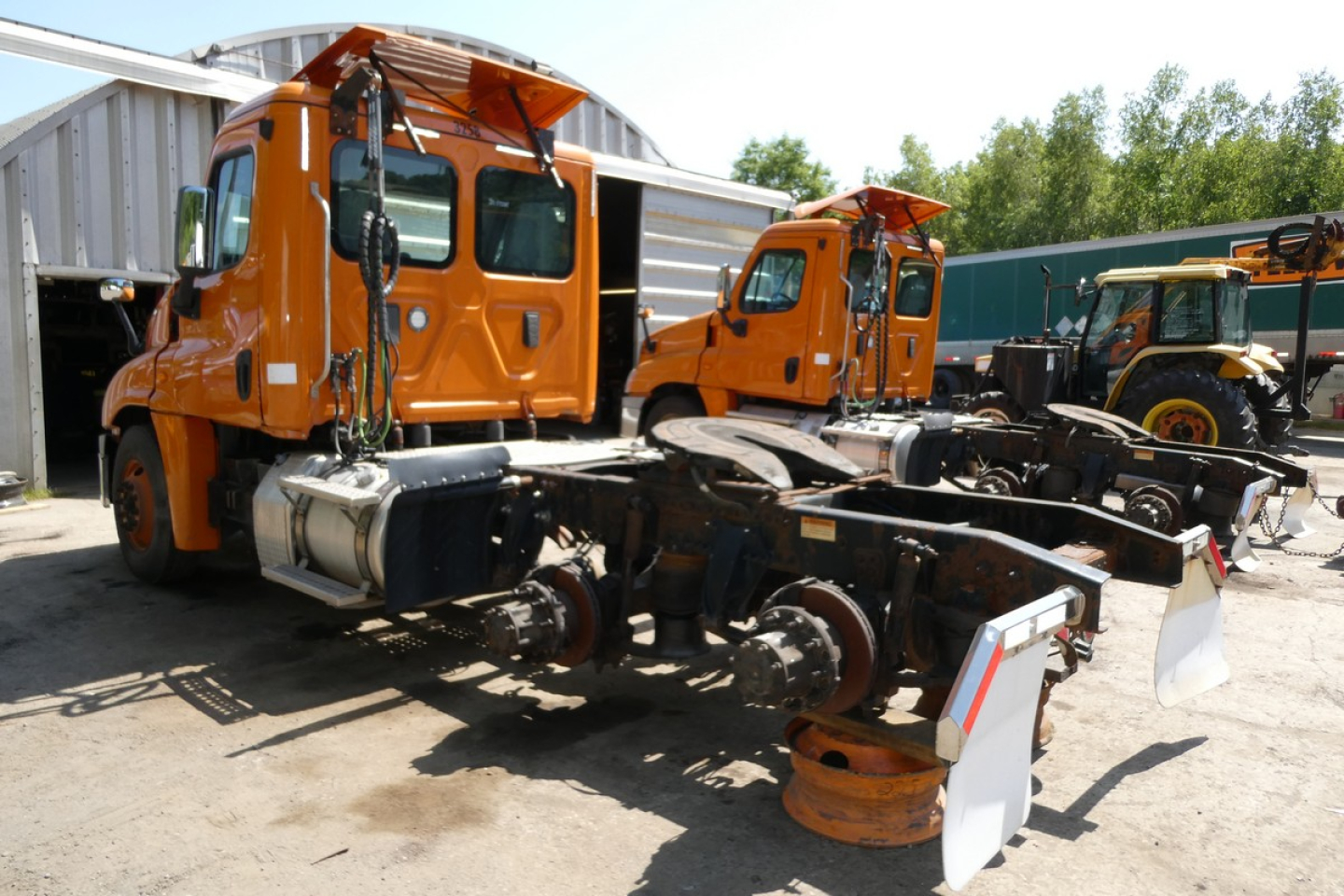 Freightliner Cascadia 125 truck chassis and cab with orange paint, no body on frame showing drive axles and suspension.