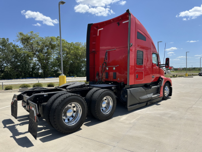 Kenworth T680 sleeper cab tractor with red exterior, rear and side view showing dual rear axles and fourth wheel, chrome rims, and black chassis components.