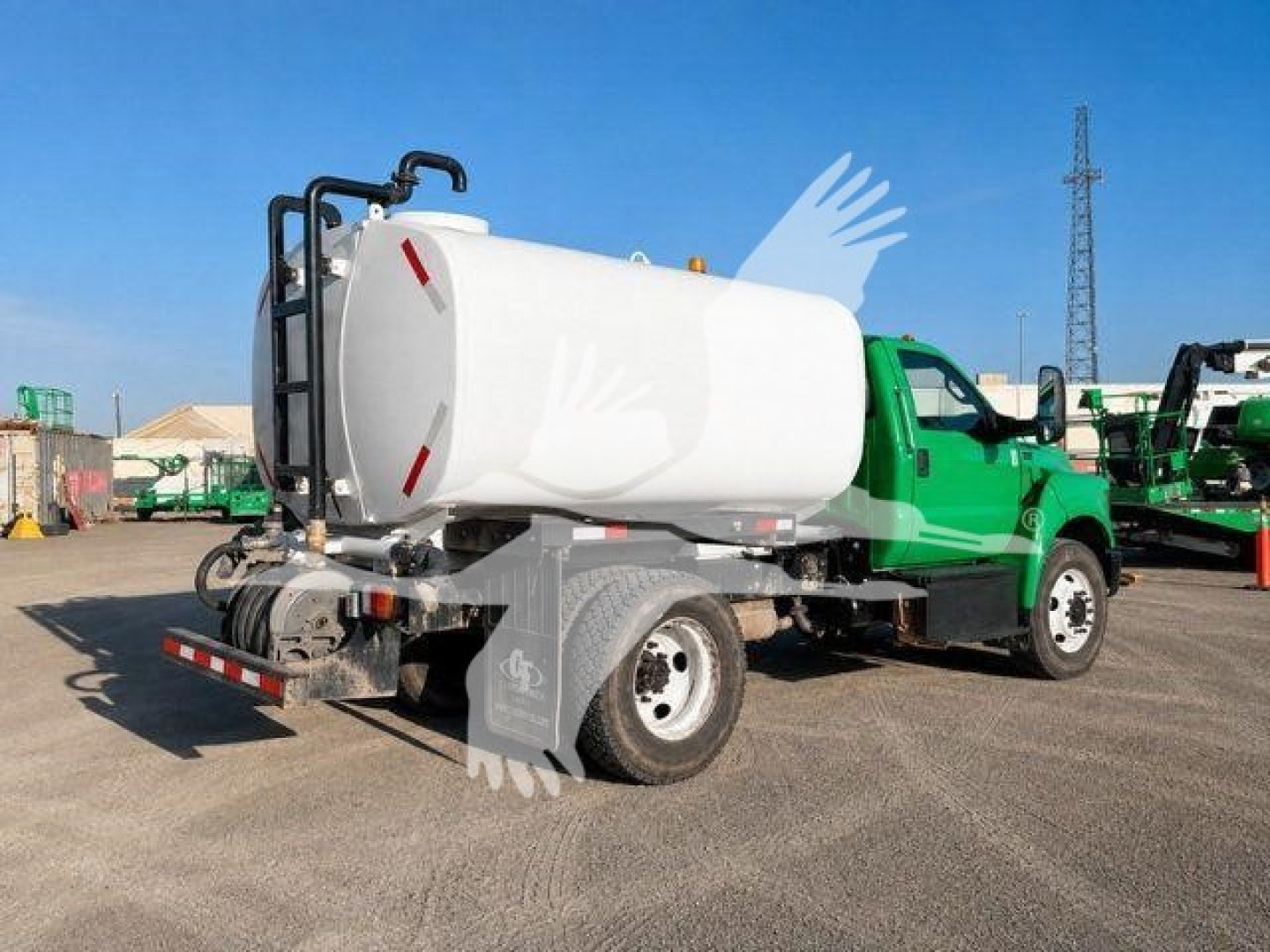 Truck-mounted water tank with white cylindrical tank on a green Ford F-650 chassis, rear view showing hoses and ladder, in a dealership lot.