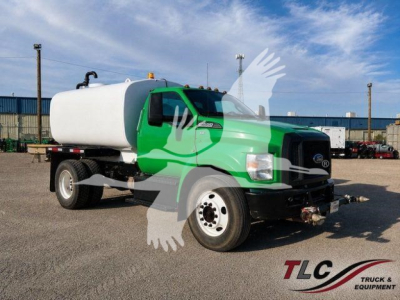 Ford F650 truck with large white tank, green cab, front view showing cargo tank and headlights.