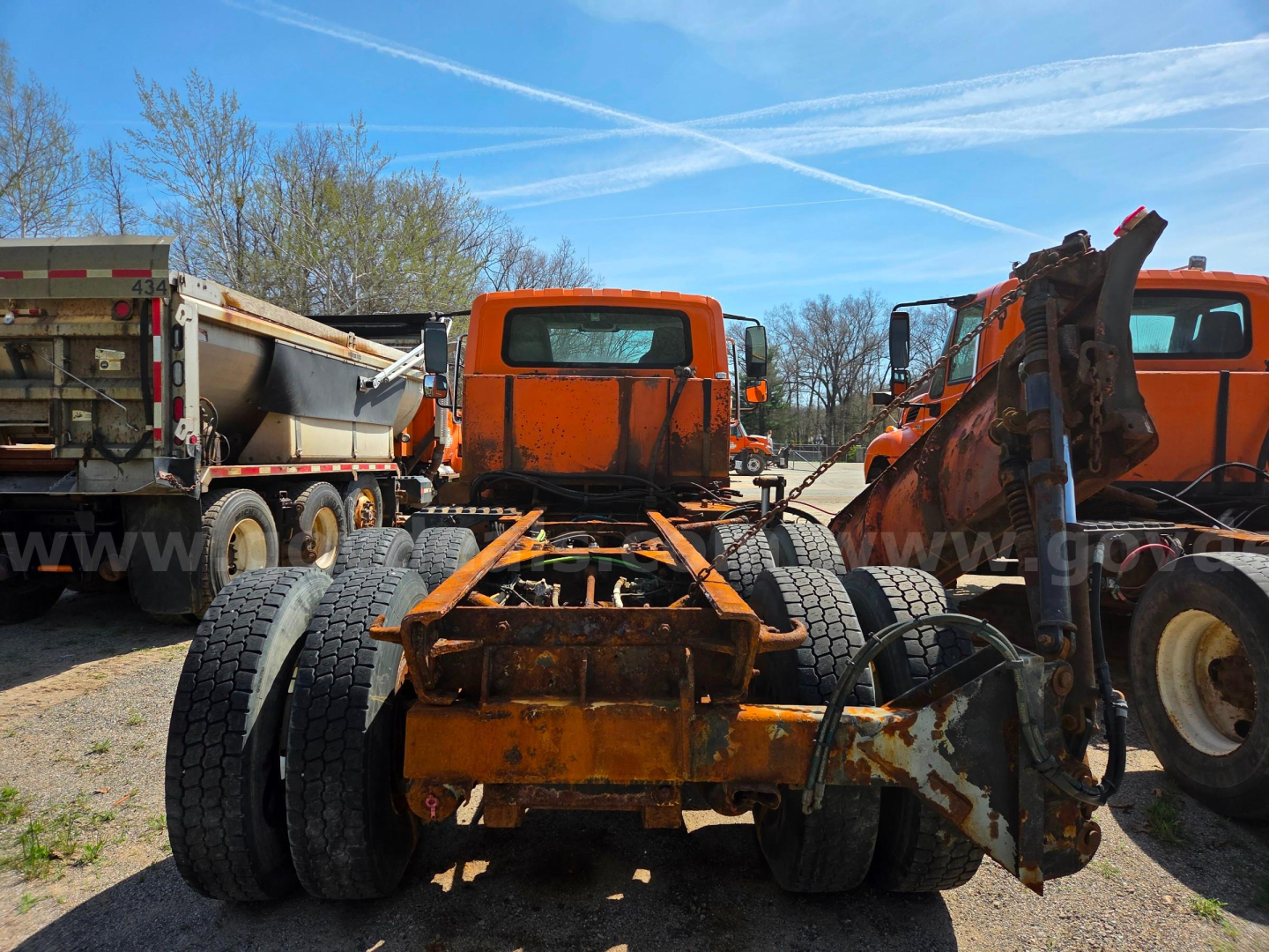 Chassis of a used 2006 International 7400 with orange frame, dual rear axles, and front hitch/frame components visible in a junkyard setting.