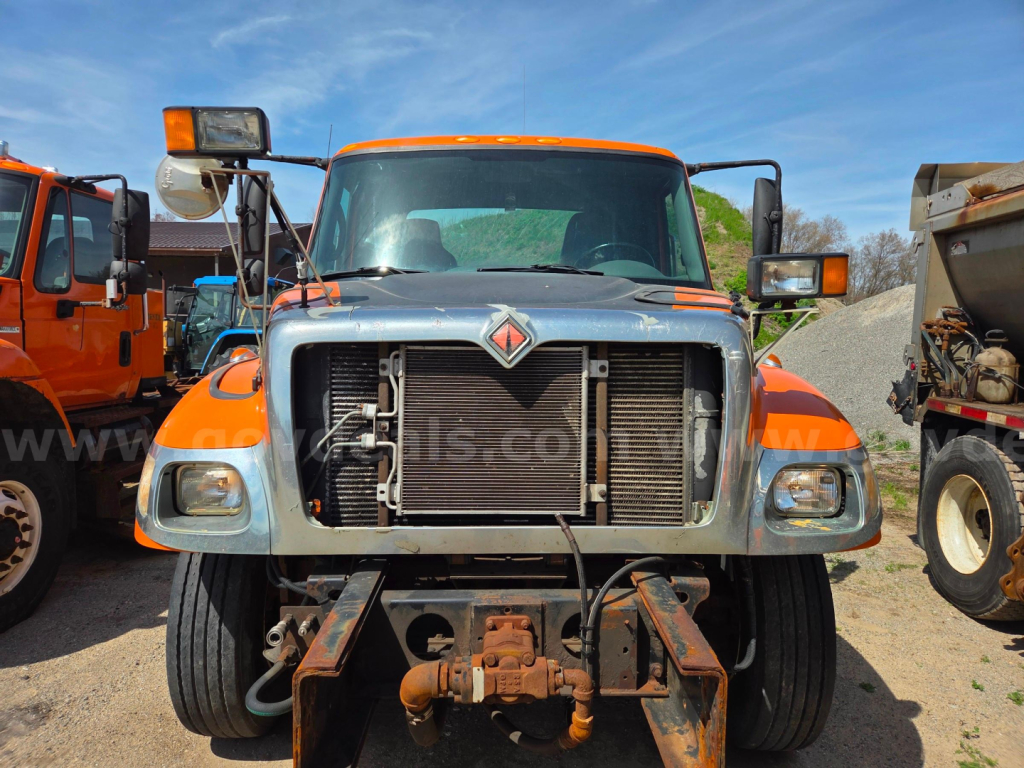 Front view of a 2006 International 7400 cab and chassis showing radiator and front hitch assembly with orange cab and headlights.