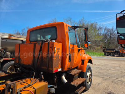 orange International 7400 cab and chassis truck rear/side view showing cab and rear cargo area with steps and dual rear wheels