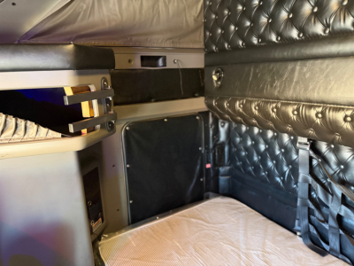 Interior sleeper cab of a 2021 Kenworth W900L with quilted black padding, side storage, and bed area visible.