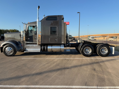 Kenworth W900L semi-truck side view showing sleeper cab and dual rear axles with chrome fuel tanks and exhaust stacks.