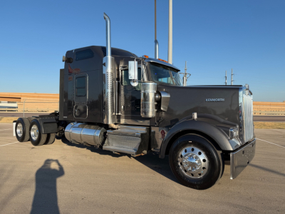Kenworth W900L conventional sleeper tractor in profile view showing chrome exhaust stacks and dual rear axles.